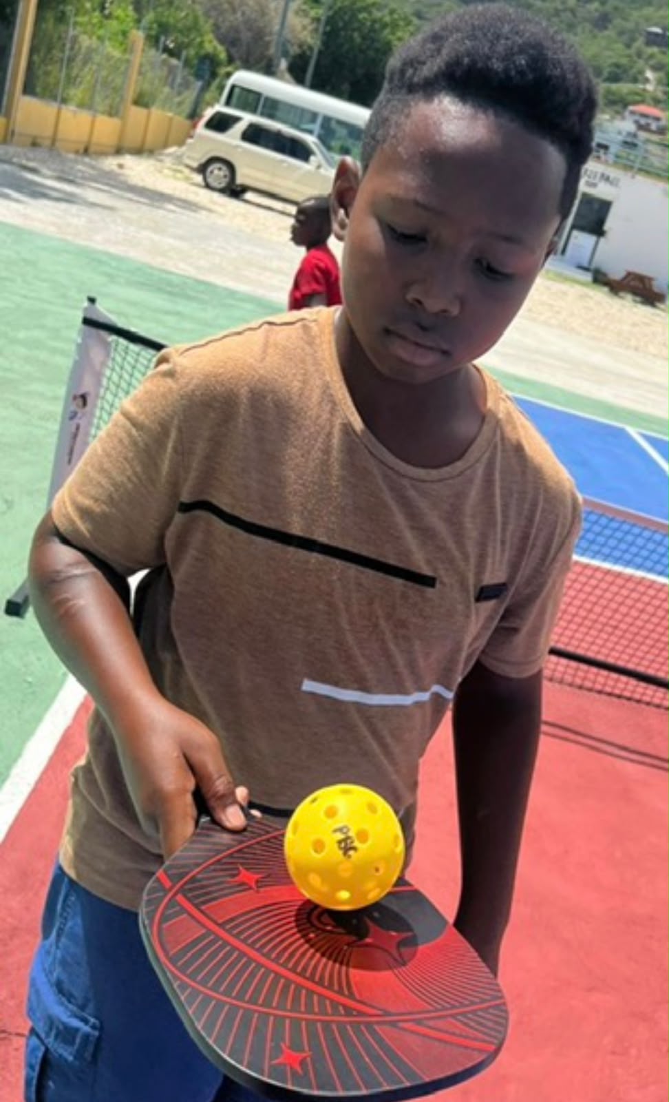 Boy balancing a pickleball on his paddle