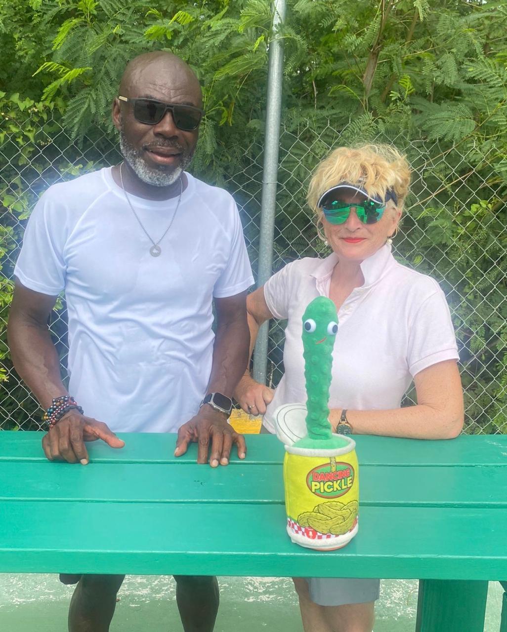 Couple posing with a plush dancing pickle toy propped on a table between them