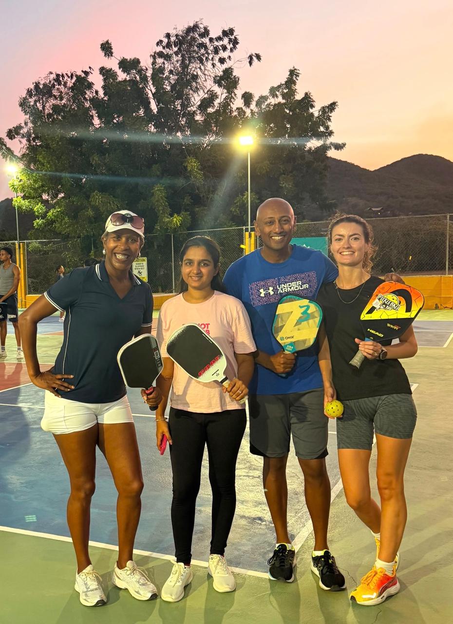 Four friends posing with paddles at sunset with hills in the background