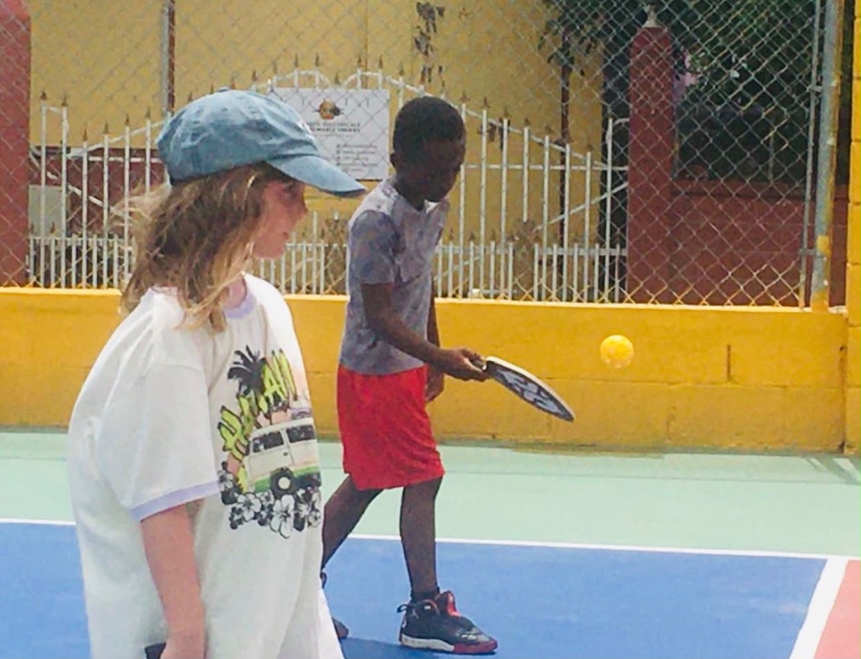 Two young players focused mid-point near the court fence