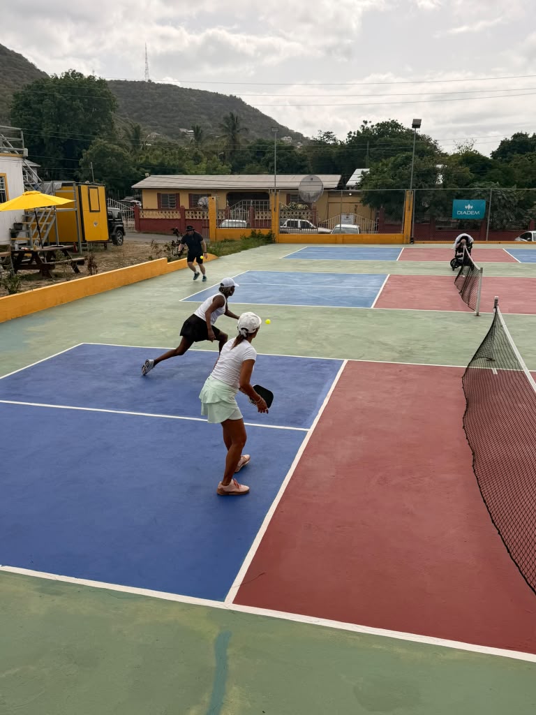 Doubles pair rushing the net together across the colourful multi-court complex