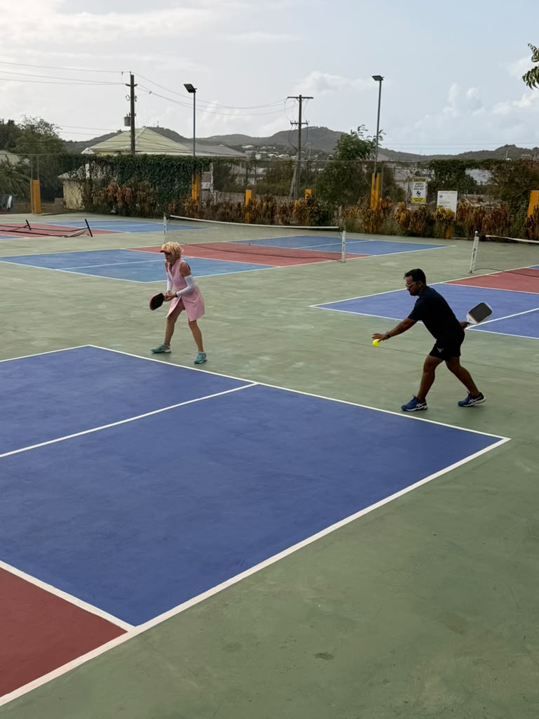 Two players rallying on court with hills and open sky in the background
