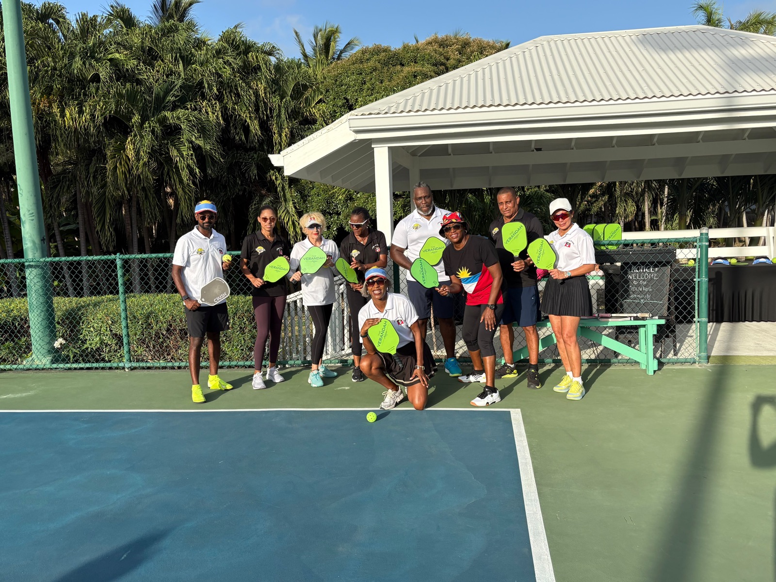 Group photo with green paddles under the pavilion at The Verandah resort courts