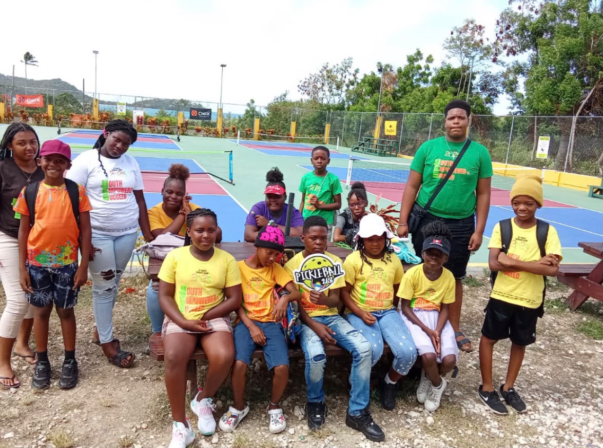 Group of youth players posing at a picnic table beside the courts